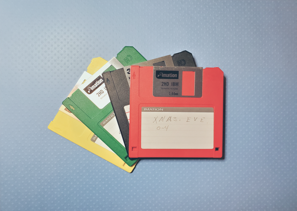 A photograph of four floppy discs on a light blue background