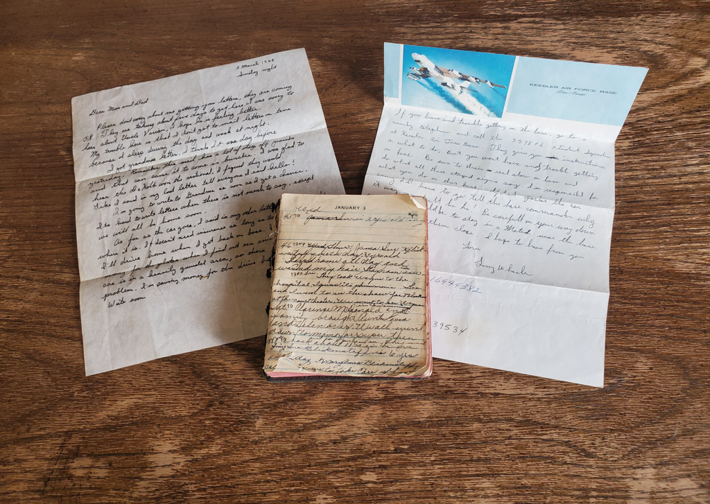 A photo of two letters and an old diary on a wood-patterned background